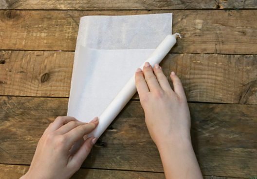 6. Kerzen diagonal in Seidenpapier einwickeln, damit beim Verdrehen des oberen Endes eine flammenähnliche Form entsteht. Zum Fixieren der losen Papierkanten empfehlen wir doppelseitiges Klebeband.