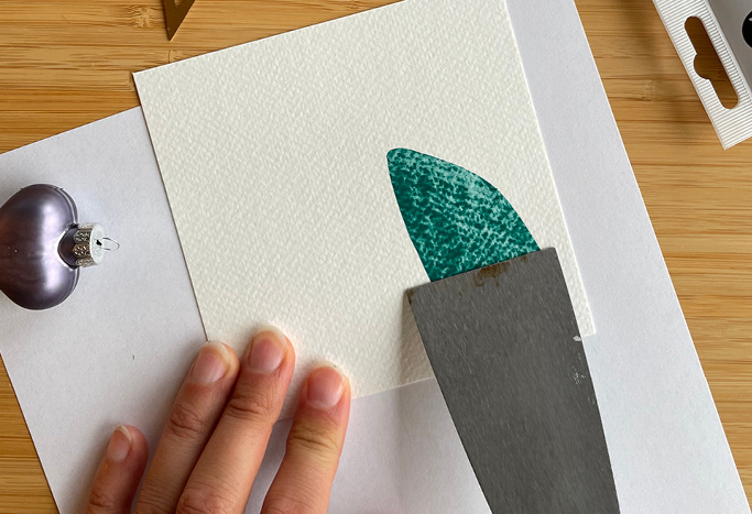 2. Nun ziehst du die Farbe mit einem Spachtel über das Papier nach unten. Dies ist der Squeeze Effekt. Nun entstehen deine Wichtel.